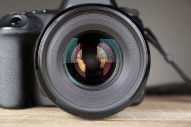 Female photographer holding professional camera on table, closeup