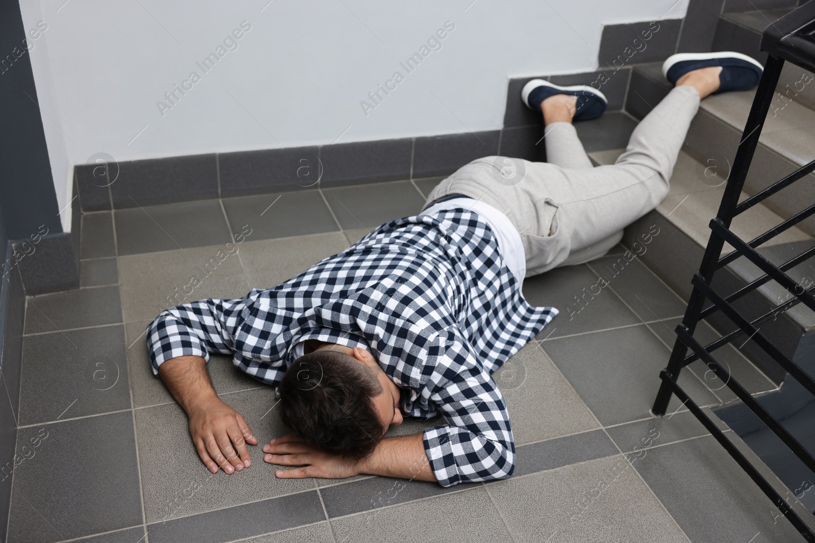 Photo of Unconscious man lying on floor after falling down stairs indoors