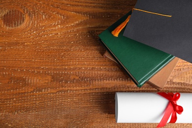 Photo of Flat lay composition with graduation hat and student's diploma on wooden table, space for text