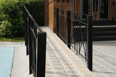 Tiled ramp with black metal railings outdoors