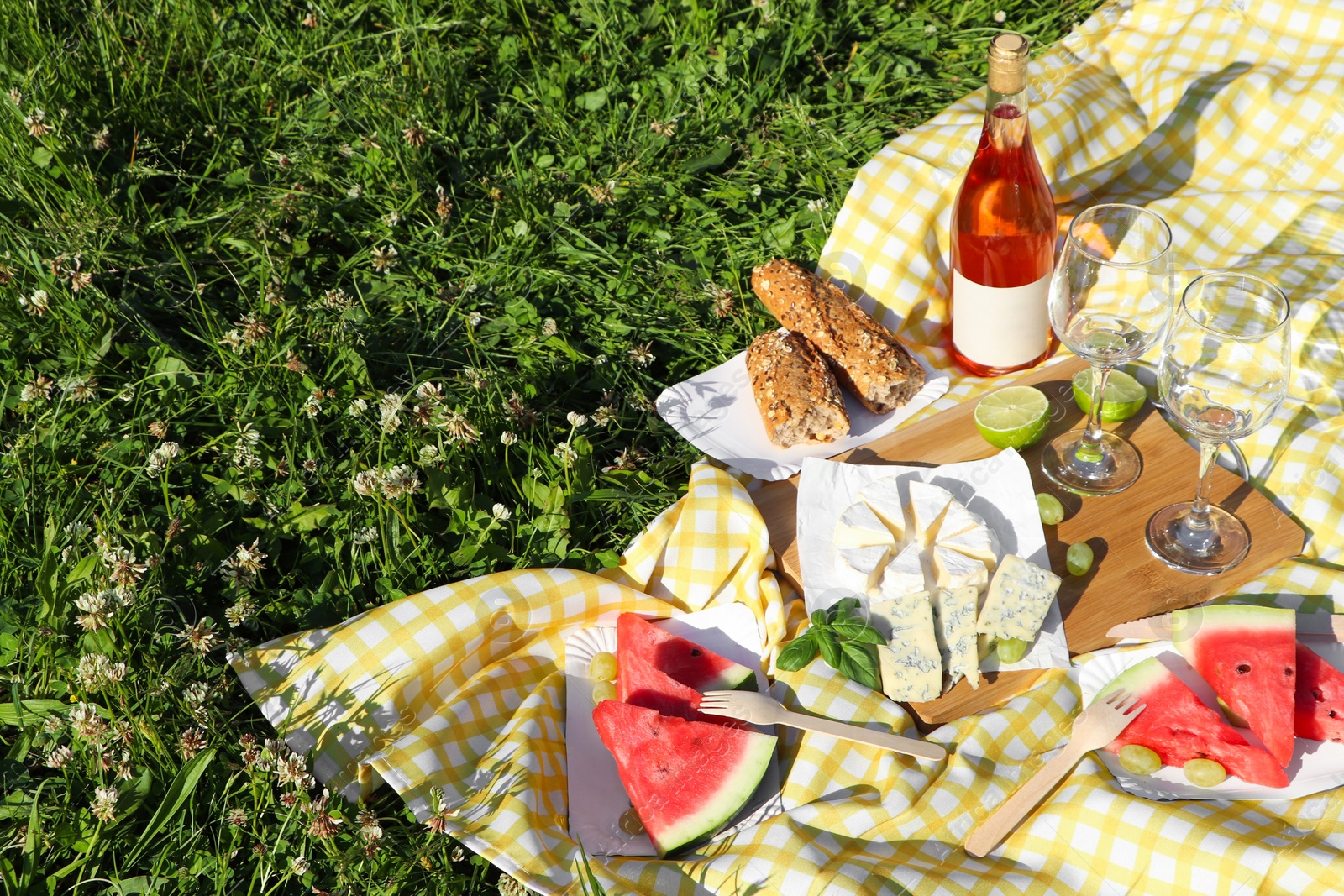 Photo of Picnic blanket with delicious food and wine on green grass outdoors