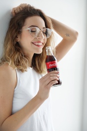 Photo of MYKOLAIV, UKRAINE - NOVEMBER 28, 2018: Young woman with bottle of Coca-Cola indoors