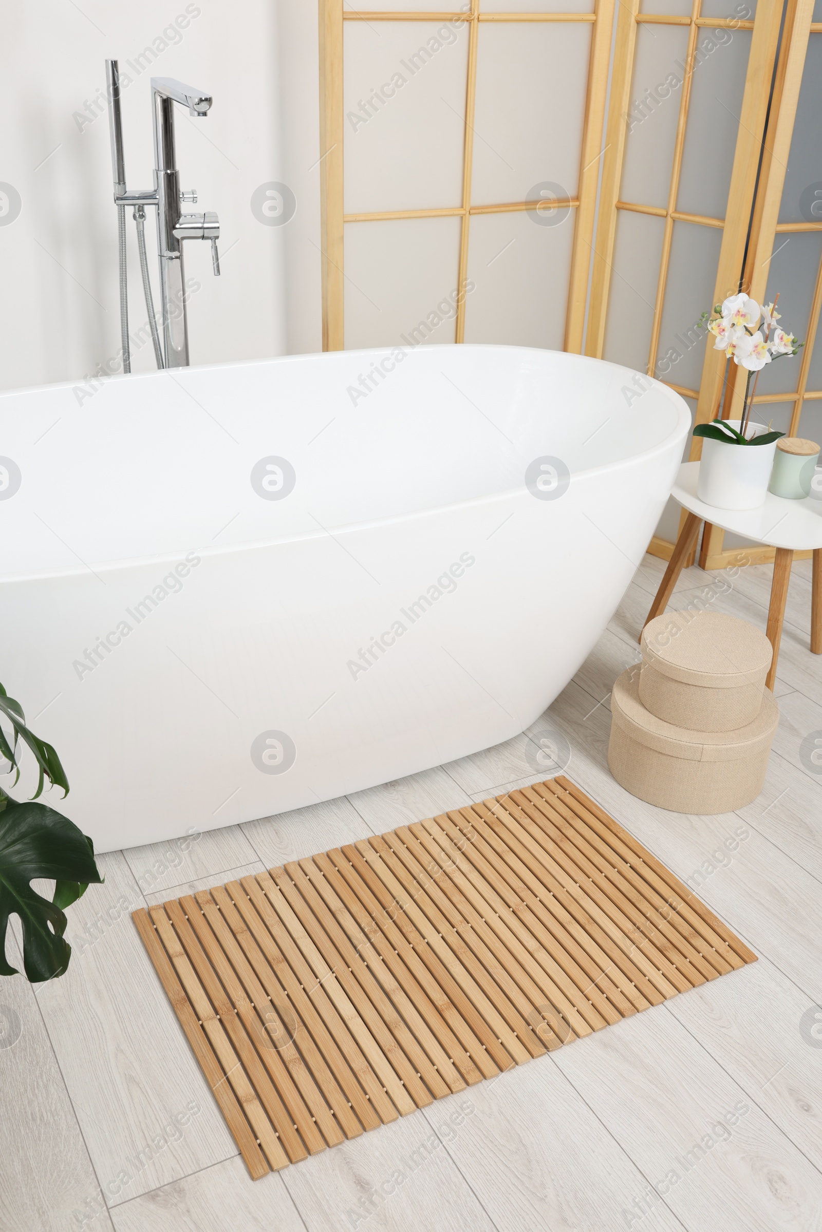 Photo of Stylish bathroom interior with bath tub and bamboo mat