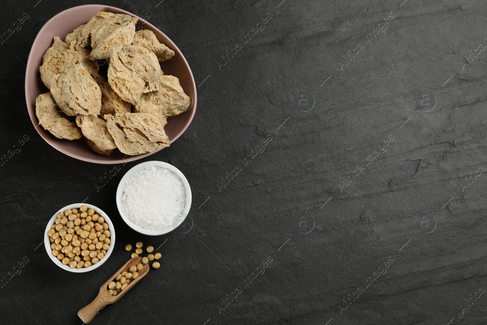 Photo of Flat lay composition with dried soy meat on black table. Space for text