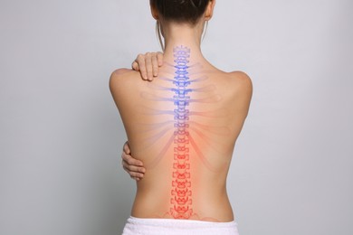 Woman suffering from pain in back on light background