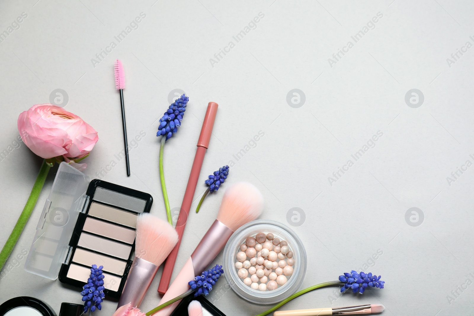 Photo of Flat lay composition with different makeup products and beautiful spring flowers on gray background, space for text