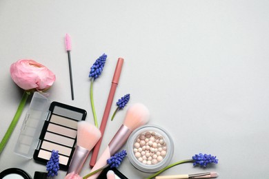 Photo of Flat lay composition with different makeup products and beautiful spring flowers on gray background, space for text