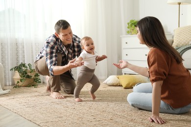 Parents supporting their baby daughter while she learning to walk at home