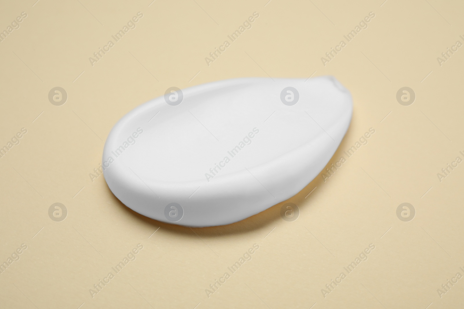 Photo of Sample of shaving foam on beige background, closeup