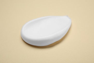 Photo of Sample of shaving foam on beige background, closeup