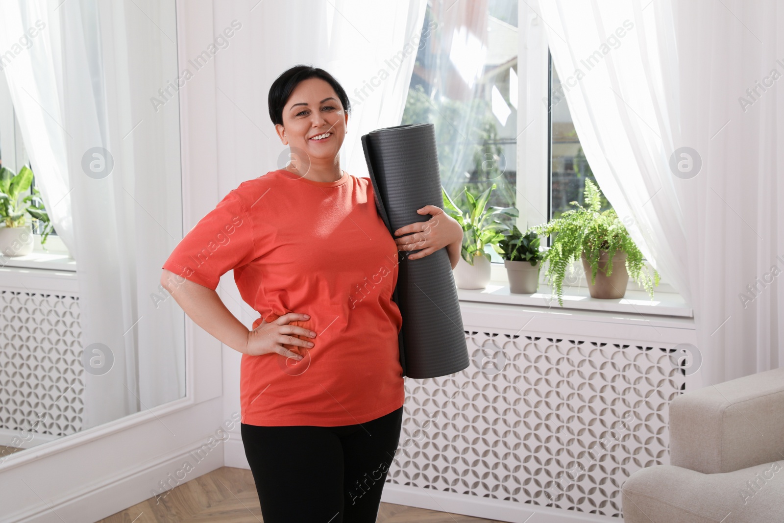 Photo of Overweight mature woman with yoga mat at home