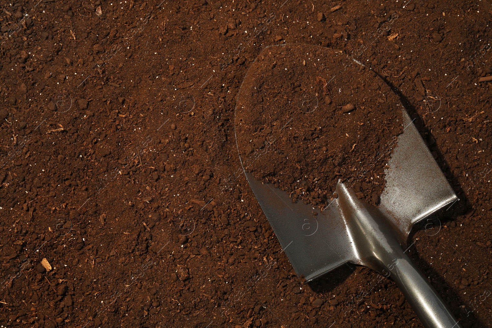 Metal shovel on fertile soil, top view and space for text. Gardening tool Photo of Metal shovel on fertile soil, top view and space for text. Gardening tool