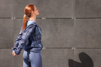 Beautiful woman in gym clothes doing exercises on street, space for text