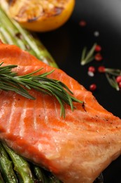 Tasty grilled salmon with asparagus and rosemary on plate, closeup