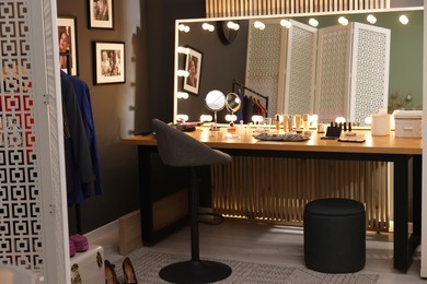 Photo of Makeup room. Stylish mirror on dressing table with different beauty products