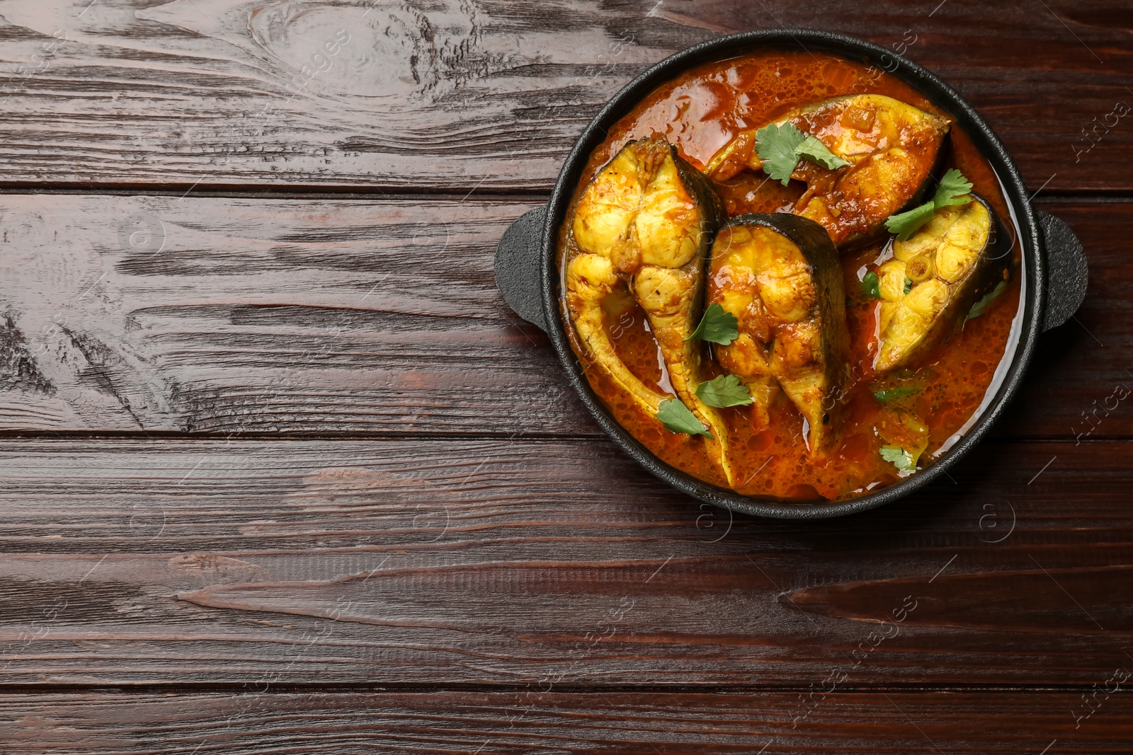 Photo of Tasty fish curry on wooden table, top view. Space for text. Indian cuisine