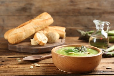 Photo of Delicious asparagus soup served on wooden table