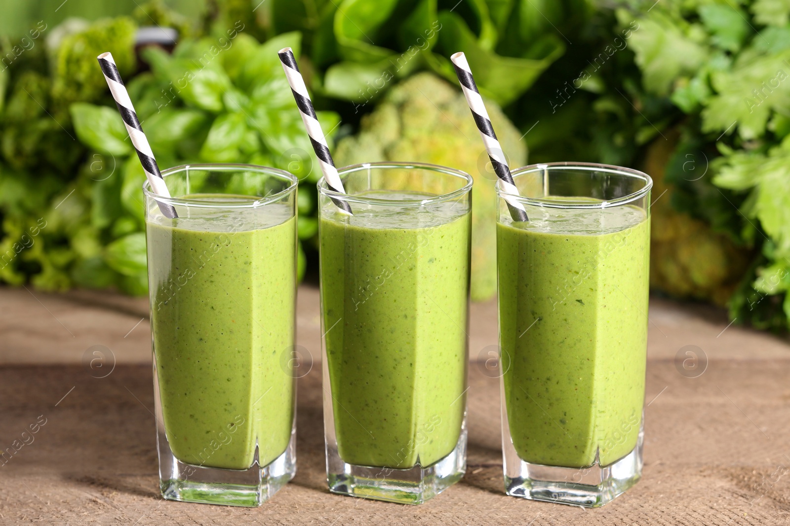 Photo of Glasses of fresh green smoothie and ingredients on wooden table