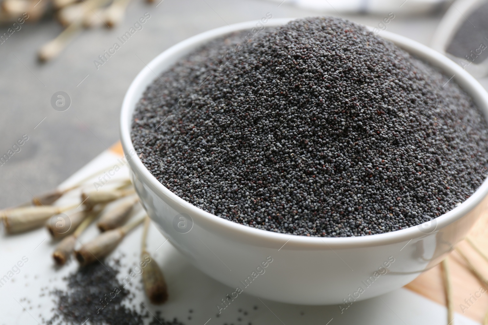 Photo of Poppy seeds in bowl on table, closeup