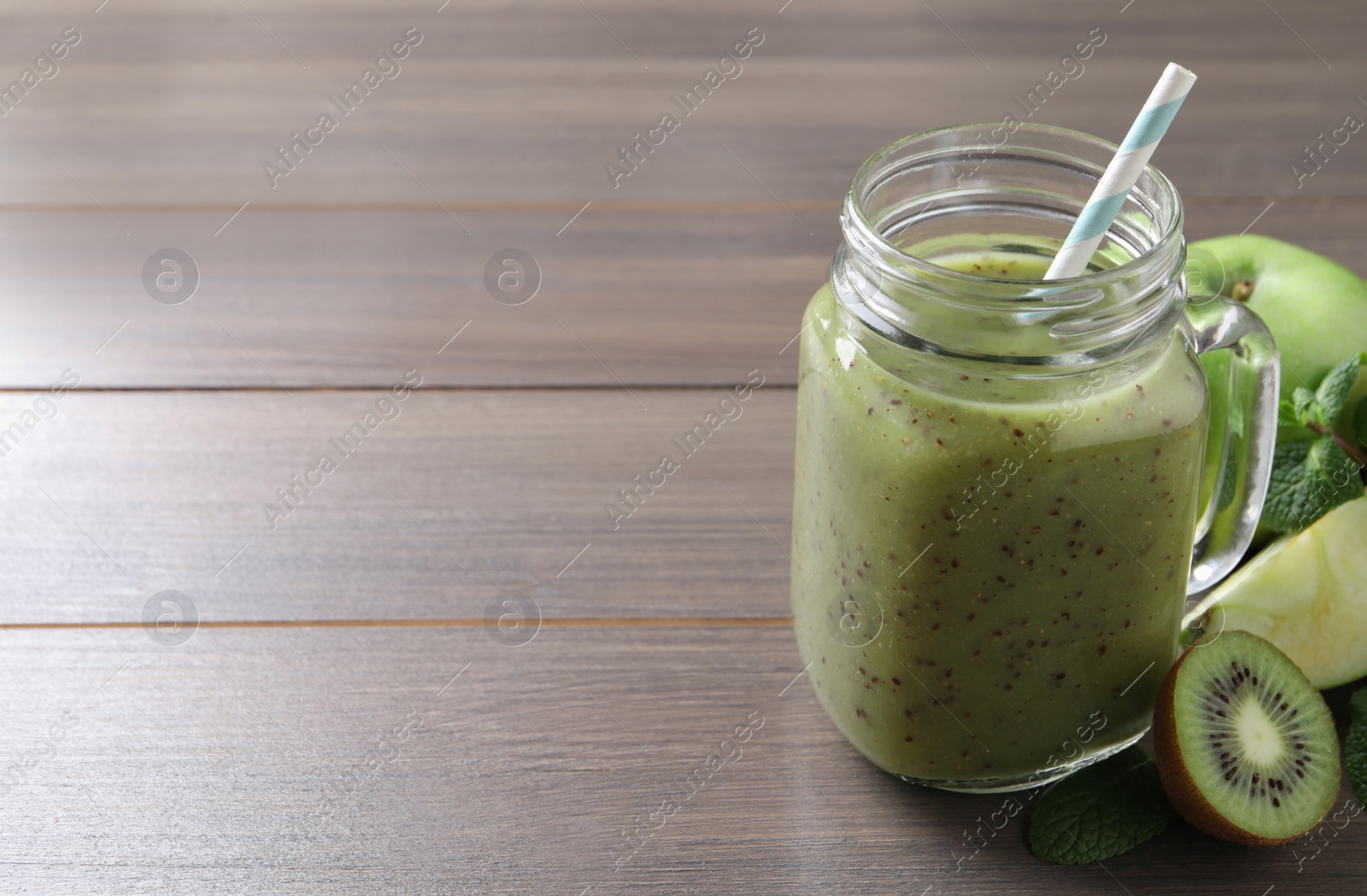 Photo of Delicious kiwi smoothie and ingredients on wooden table. Space for text