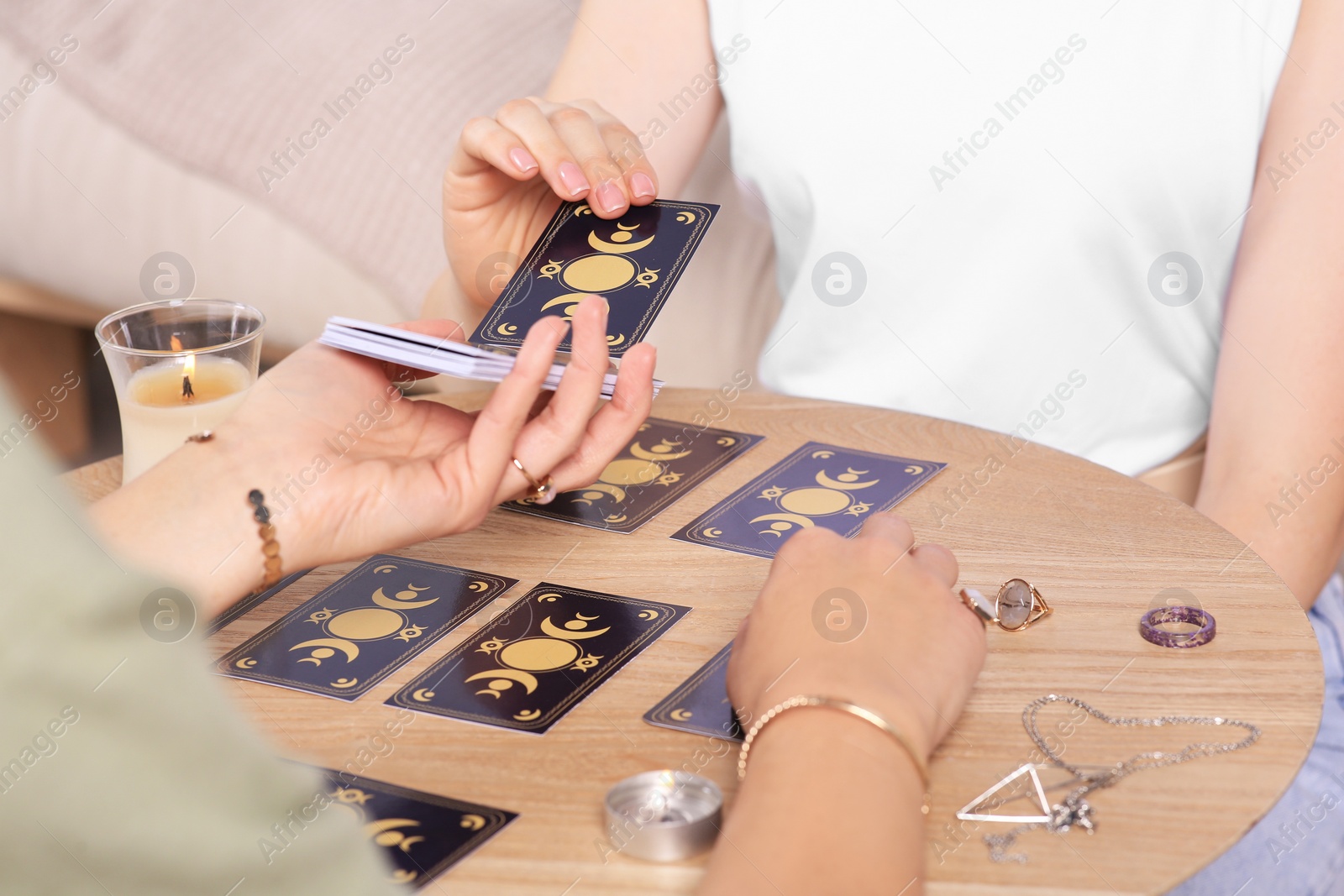 Photo of Woman pulling one tarot card at table indoors, closeup. Fortune telling