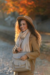 Portrait of beautiful African-American woman with stylish beige backpack on city street