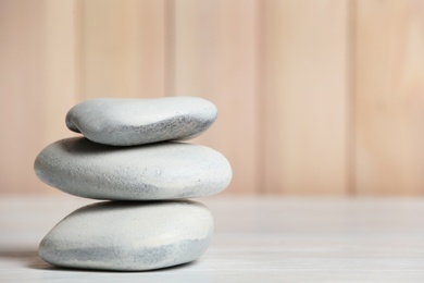 Photo of Spa stones on table against blurred background. Space for text