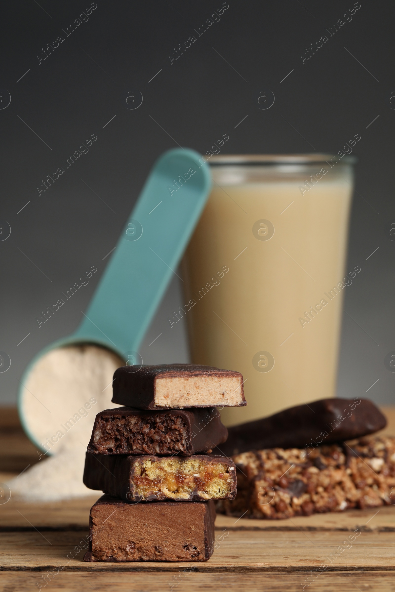 Photo of Different energy bars, protein cocktail and powder on wooden table