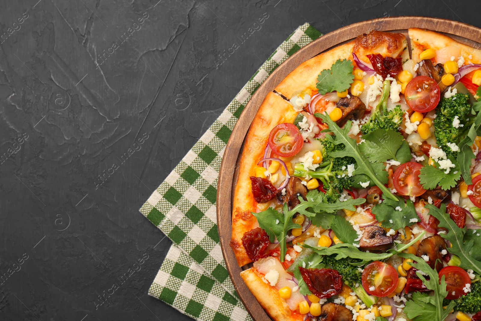 Photo of Delicious vegetarian pizza with cheese, mushrooms, vegetables and greens on black table, top view. Space for text