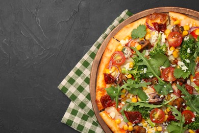 Photo of Delicious vegetarian pizza with cheese, mushrooms, vegetables and greens on black table, top view. Space for text