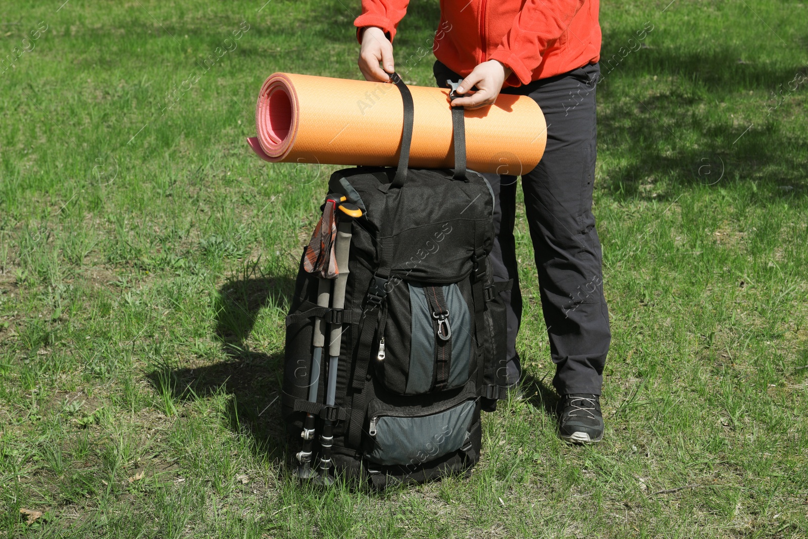 Photo of Hiker fastening mat on backpack outdoors, closeup