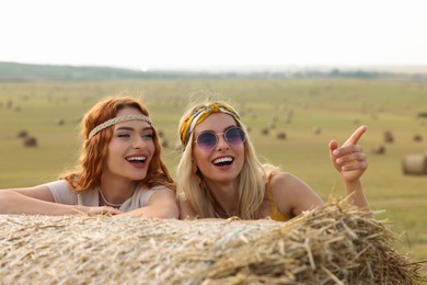 Photo of Beautiful hippie women near hay bale in field