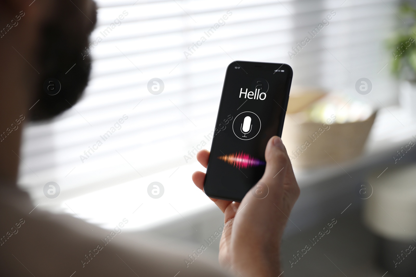 Image of Man using voice search on smartphone indoors, closeup