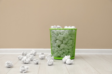 Metal bin with crumpled paper against color wall