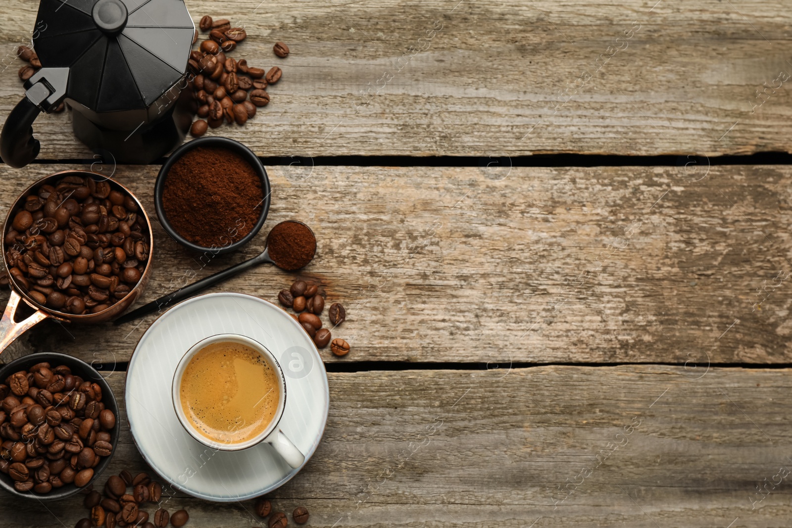 Photo of Coffee maker, beans, powder and cup of drink on wooden table, flat lay. Space for text