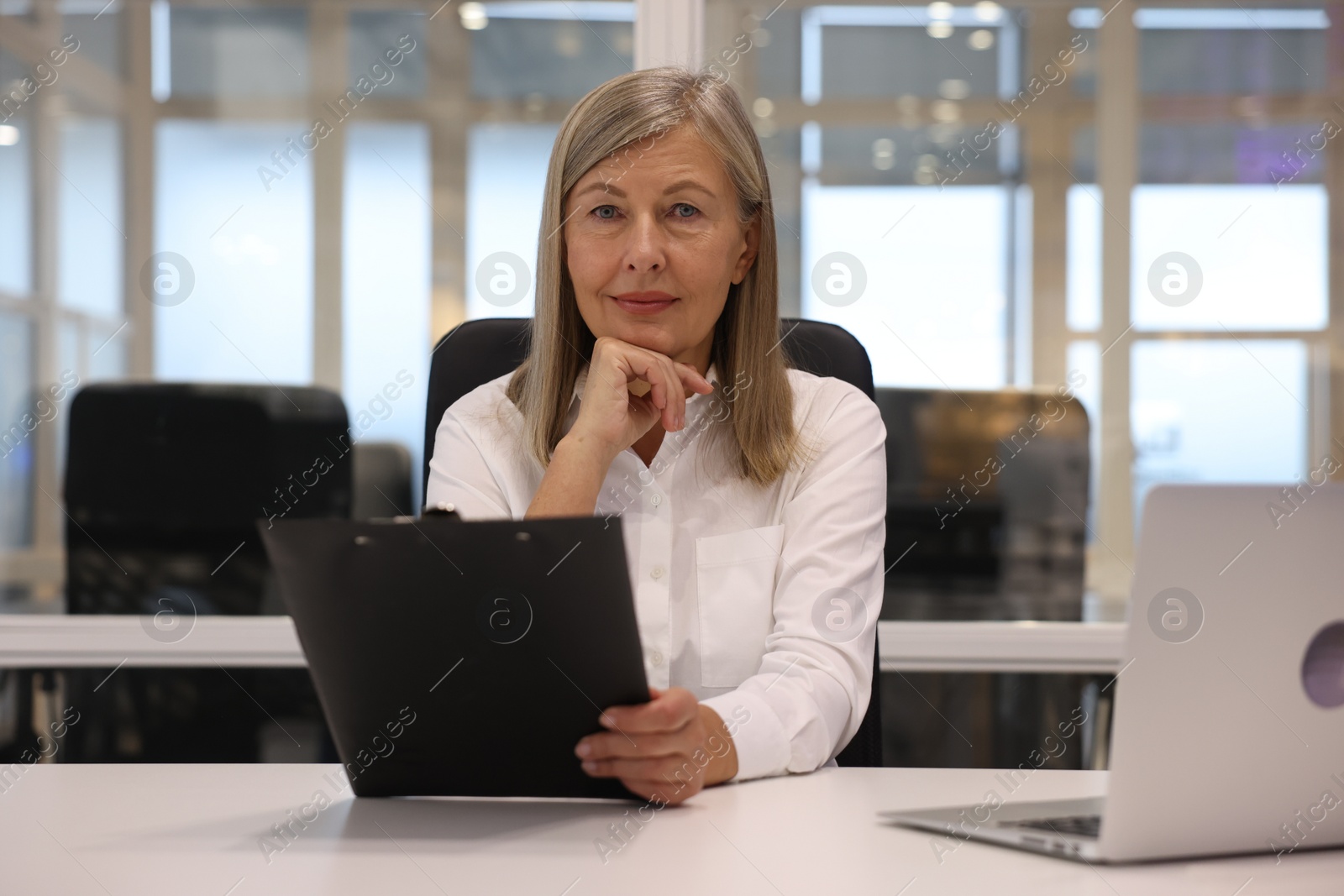 Photo of Confident woman with clipboard and laptop working in office. Lawyer, businesswoman, accountant or manager