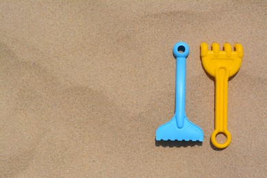 Photo of Colorful plastic rakes on sand, space for text. Beach toys