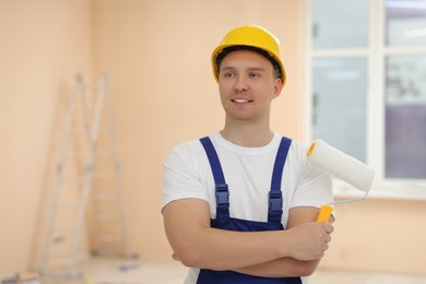 Worker holding paint roller in unfinished room. Space for text