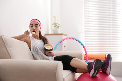 Lazy young woman eating ice cream instead of training at home