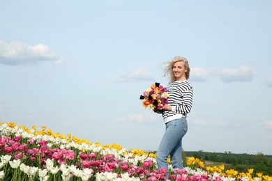 Photo of Happy woman with spring bouquet of flowers in beautiful tulip field on sunny day