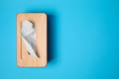 Photo of Holder with paper tissues on light blue background, top view. Space for text