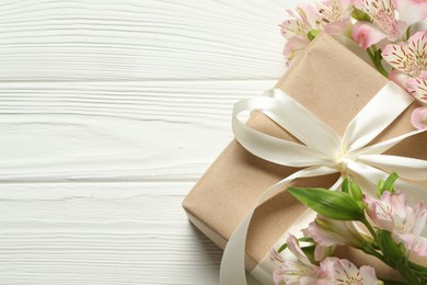 Photo of Happy Mother's Day. Beautiful flowers and gift box on white wooden table, flat lay. Space for text