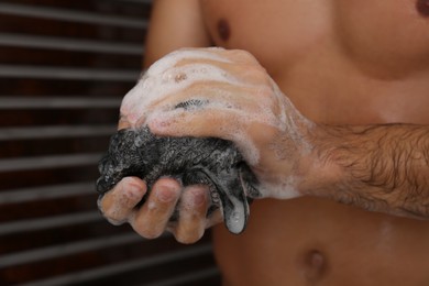 Man with mesh pouf taking shower at home, closeup