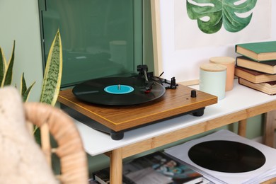 Photo of Stylish turntable with vinyl record on console table in room