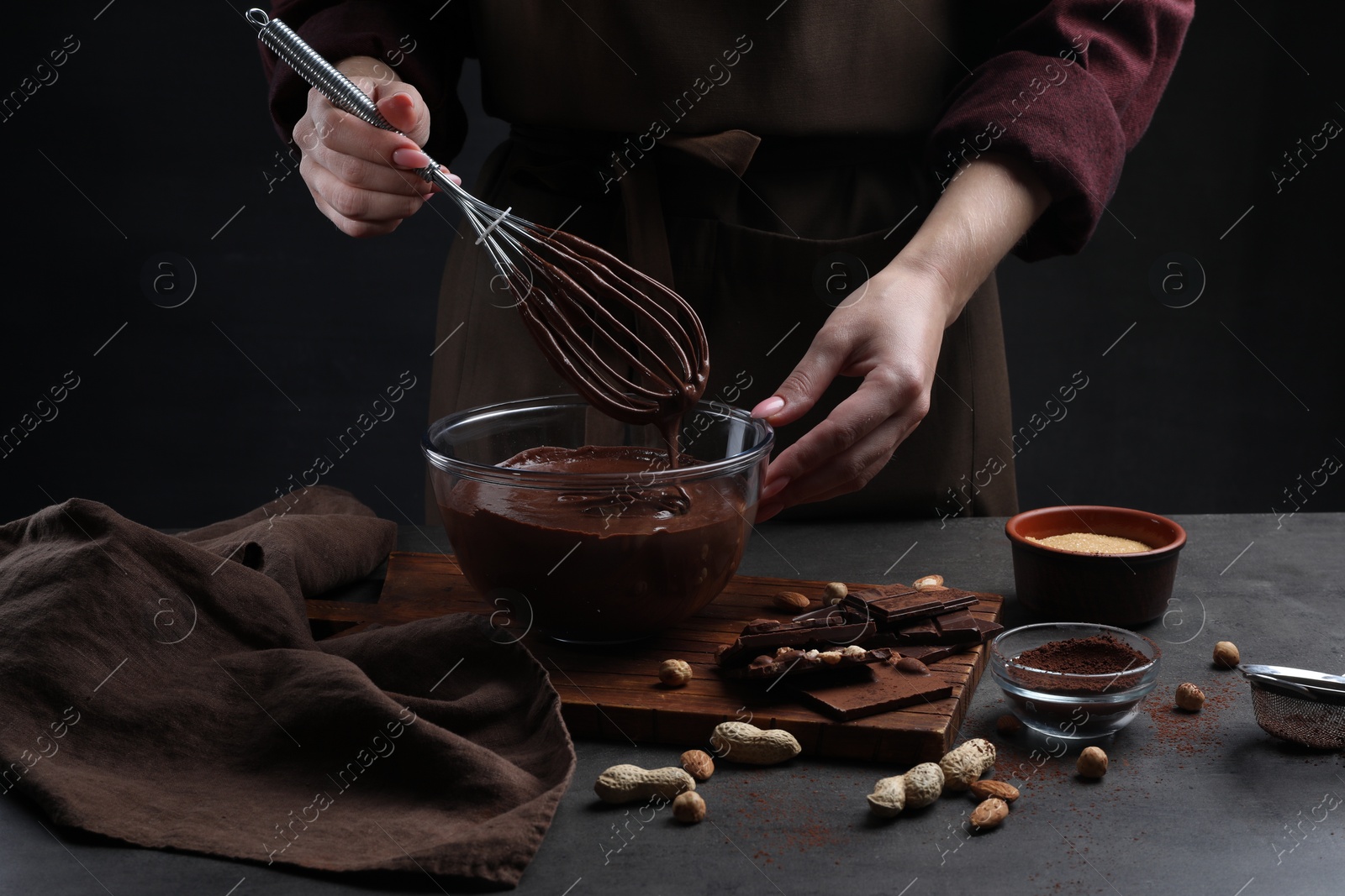 Photo of Woman with whisk mixing delicious chocolate cream at table, closeup