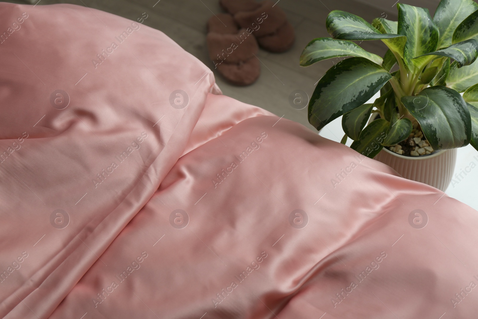 Photo of Closeup view of bed with beautiful pink silk linens indoors