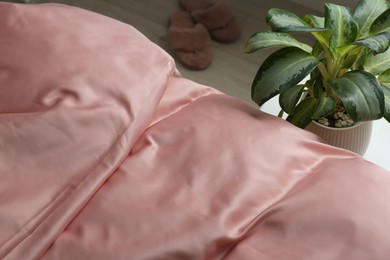 Photo of Closeup view of bed with beautiful pink silk linens indoors