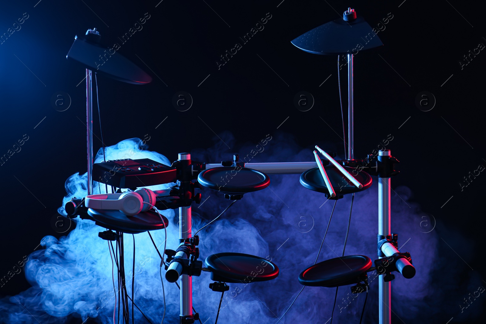 Photo of Modern electronic drum kit and smoke on dark background, color toned. Musical instrument