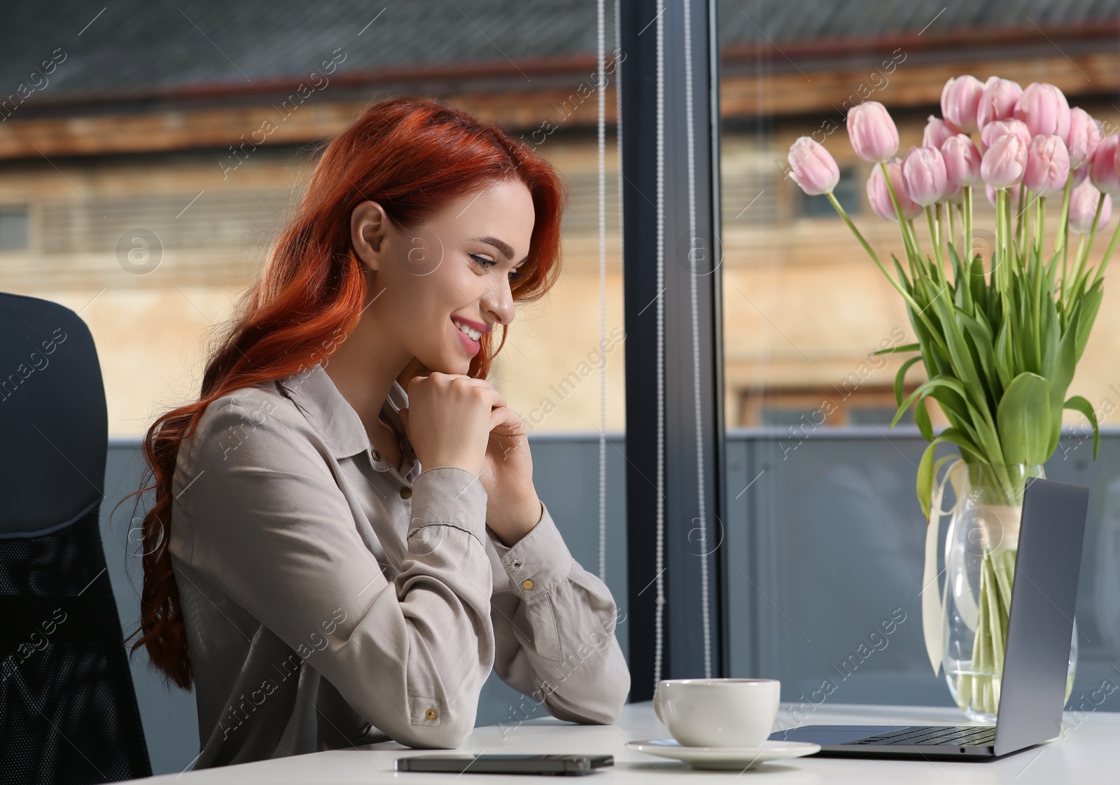 Photo of Happy woman working with laptop at white desk in office