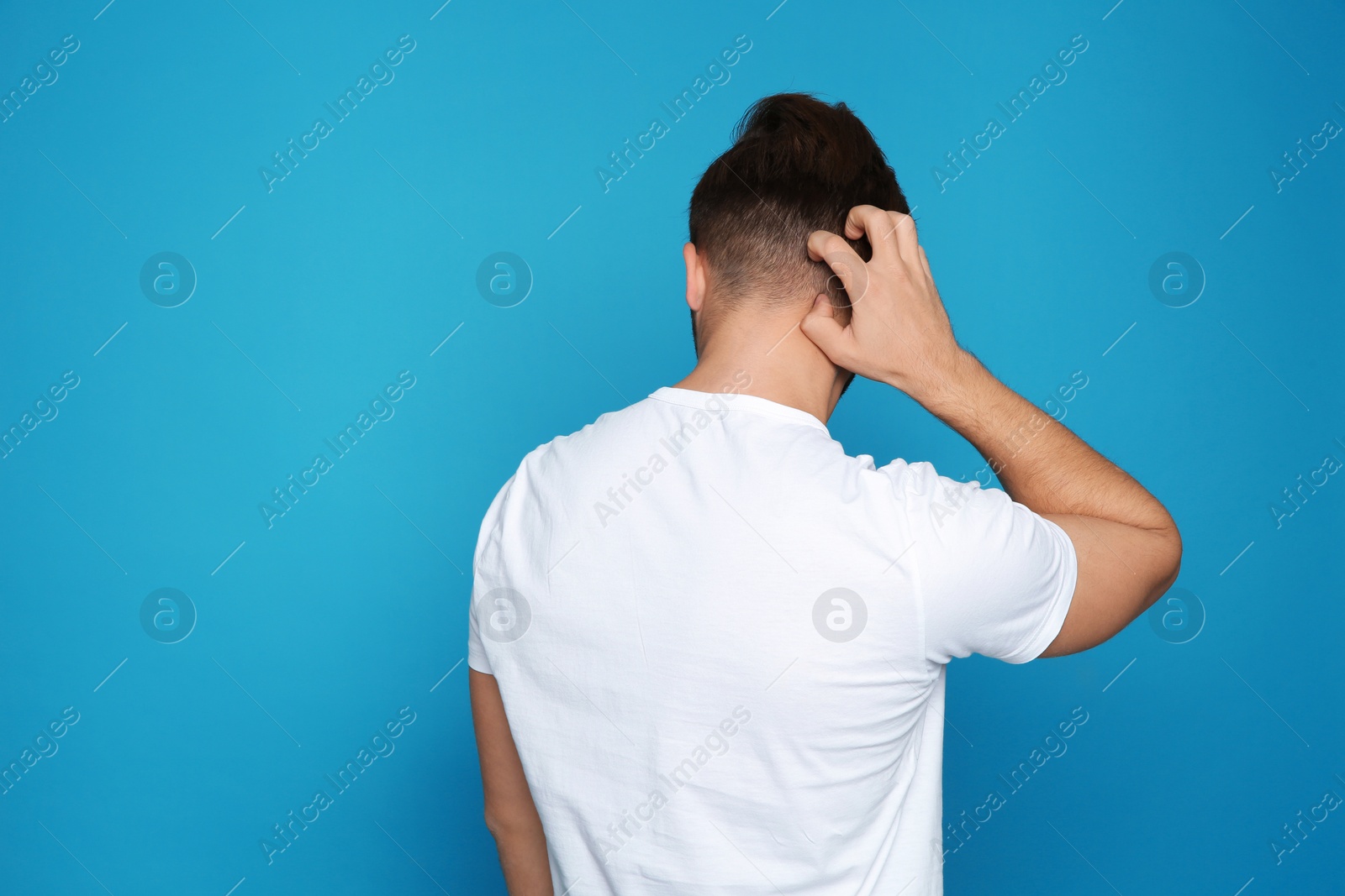 Photo of Young man scratching head on color background, space for text. Annoying itch